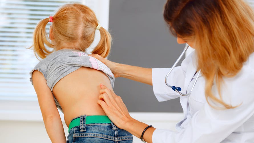 Une médecin examine le dos d'un enfant
