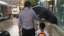 La photo d’un papa, tenant un parapluie pour protéger son
  fils, fait le buzz