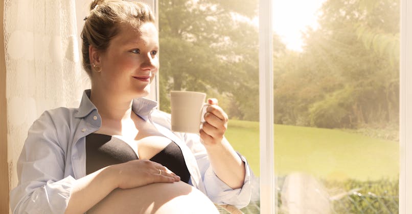 Une femme enceinte boit une tasse de thé ou de café