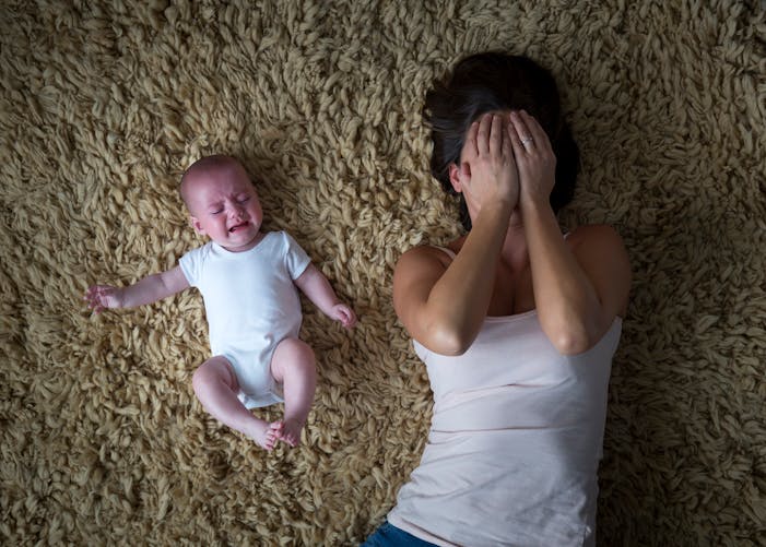 un bebe pleure à côte de sa mère