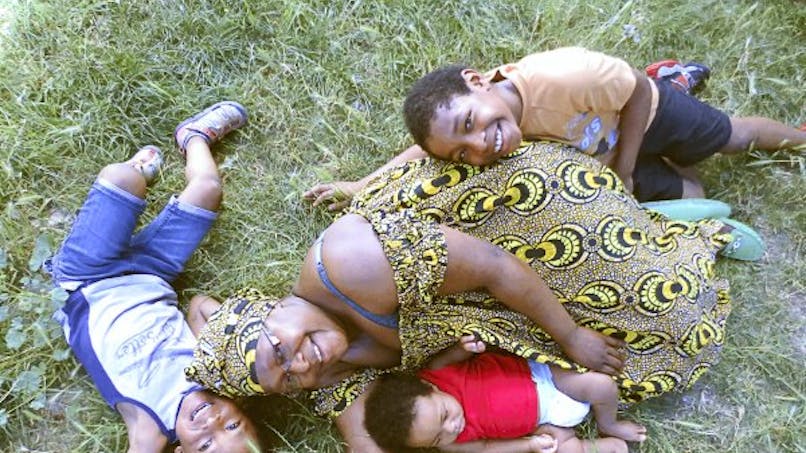 Une maman allongée dans l'herbe avec ses enfants