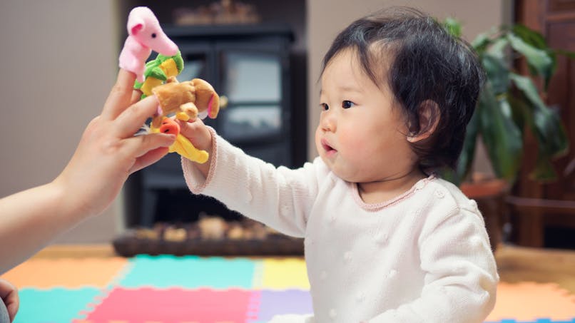 un bébé joue avec des marionnettes à doigts 