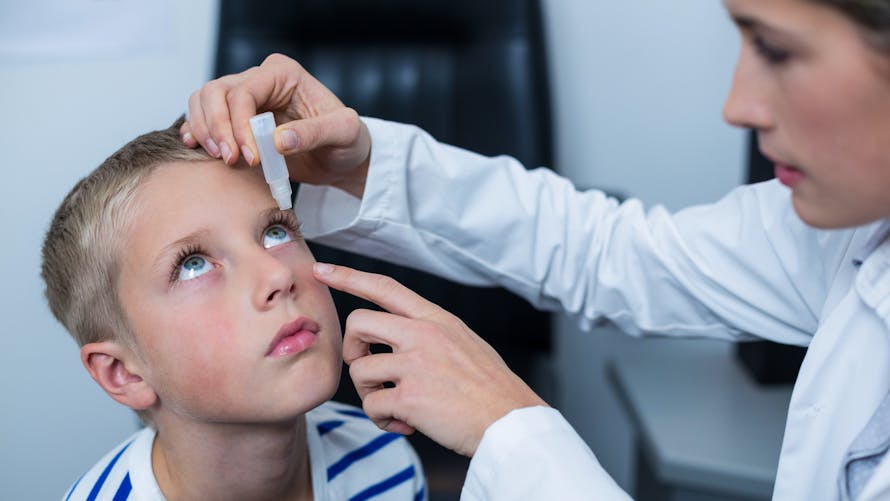 médecin mettant du collyre dans l'oeil d'un enfant
