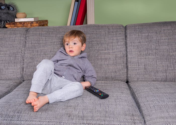 enfant assis sur un canapé et régardant la tv