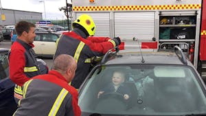 Un petit garçon coincé dans une voiture passe un bon moment avec les pompiers