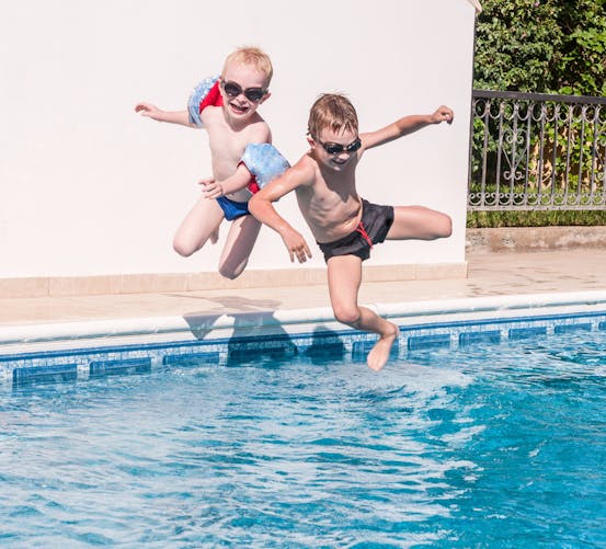 2 garçons sautant dans une piscine privée