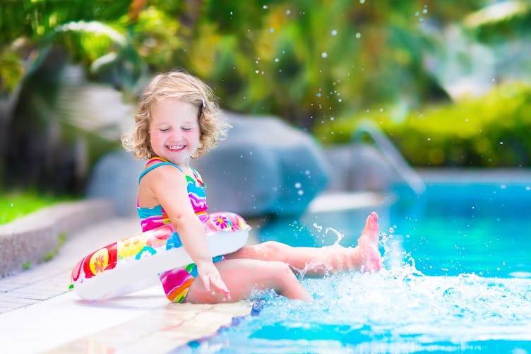 Petite fille avec bouée autour de la taille au bord de la piscine