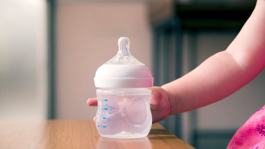 main de bébé sur biberon d'eau