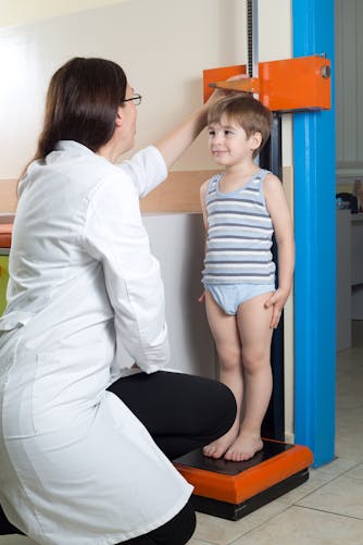 médecin scolaire mesurant un petit garçon