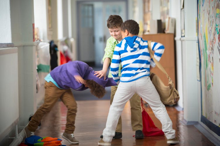3 enfants se battant dans les couloirs de l'école