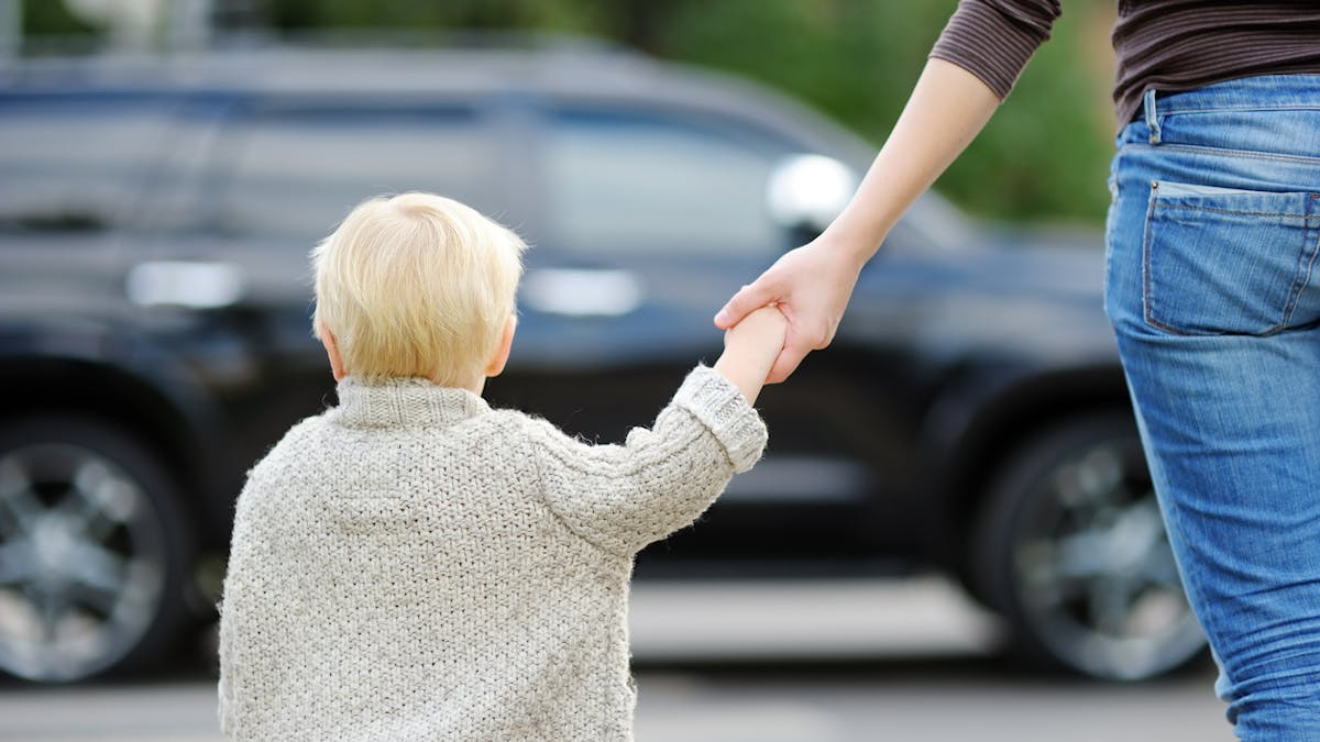 enfant donnant la main à sa mère en traversant la rue