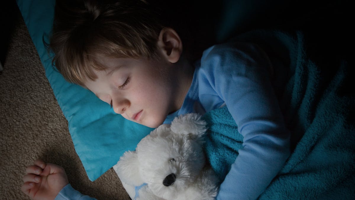 petit garçon dormant avec un ours en peluche dans les bras