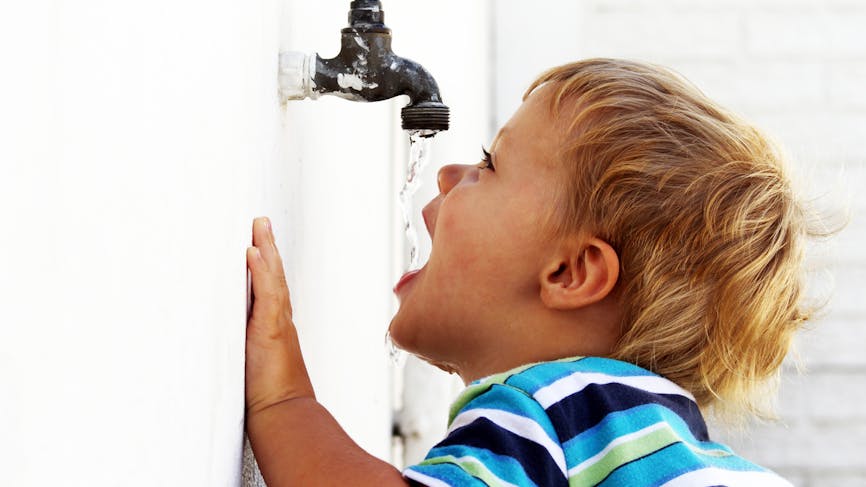 enfant buvant de l'eau à un robinet