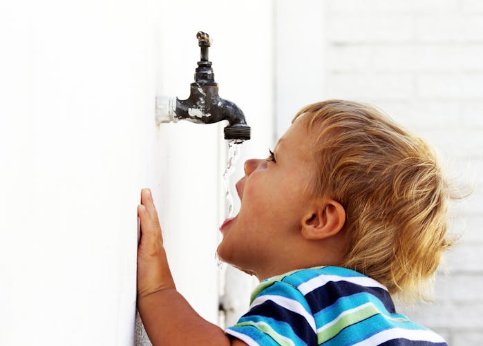 enfant buvant de l'eau à un robinet