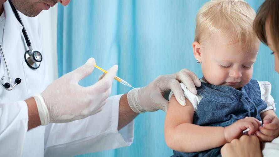 bébé se faisant vacciner dans les bras de sa maman