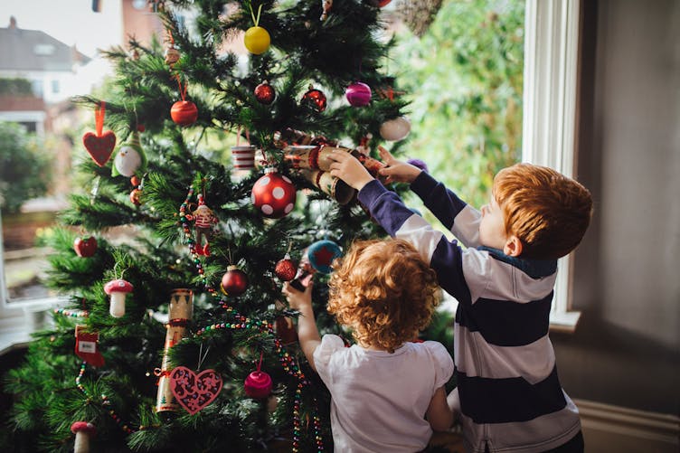 Enfants décorant un sapin de Noël