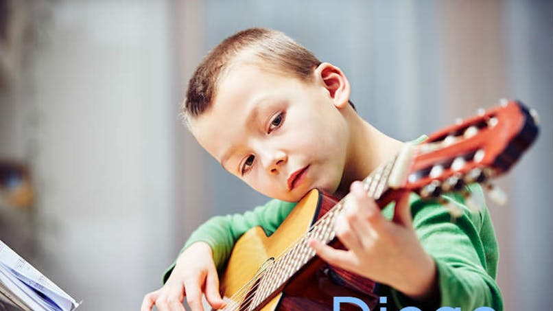 un garçon gratte quelques accords sur sa guitare