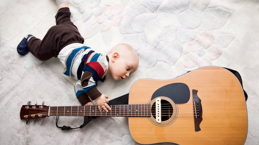 un bébé avec une guitare dans les mains