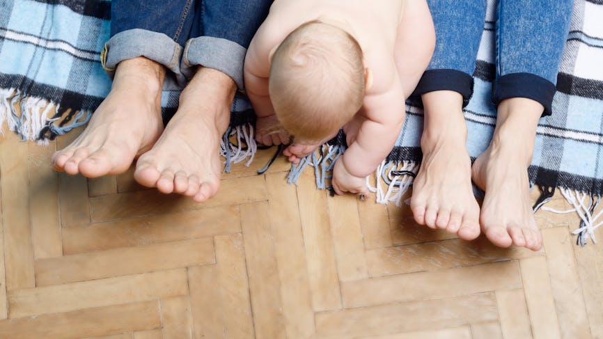 Un bébé entre les pieds de ses parents