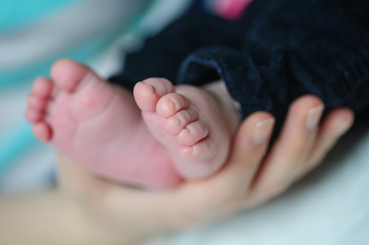 pieds de bébé dans la main d'une maman