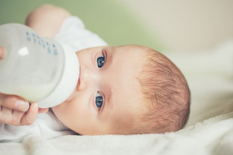 un bébé boit du lait au biberon