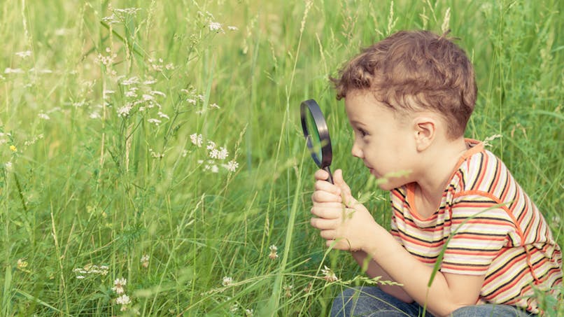 un enfant avec une loupe dans l'herbe