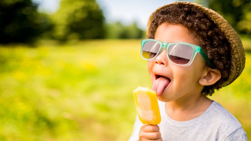un garçon mange une glace en été