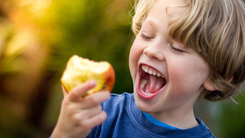 un garçon croque dans une pomme