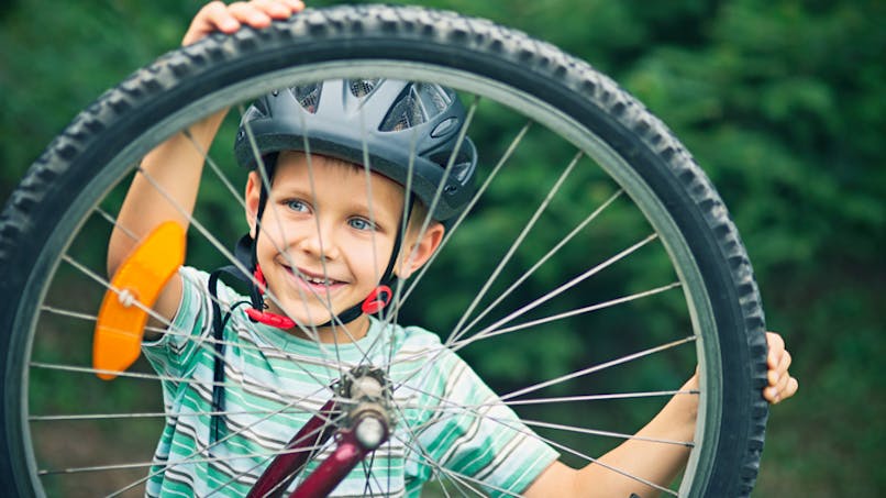 un enfant tient sa roue de vélo