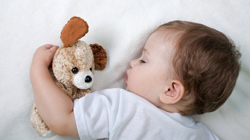 un bébé dort avec son doudou