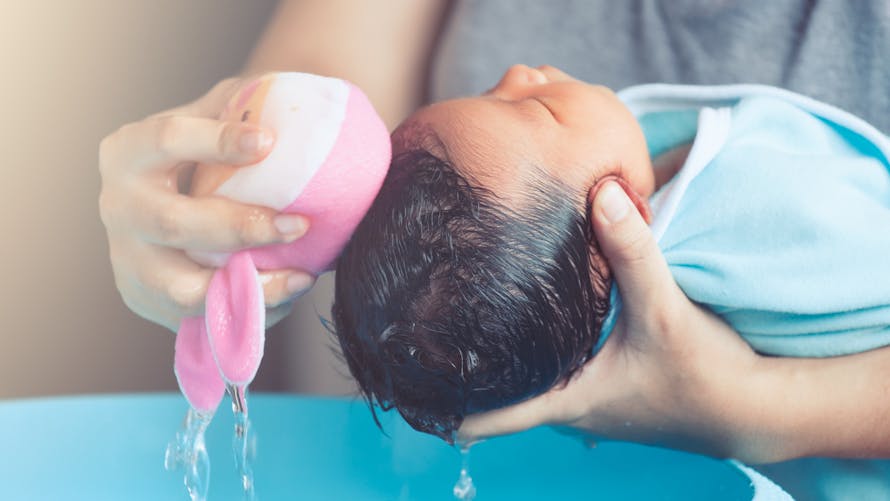 premier shampoing de bébé avec une éponge