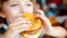 Alimentation : un enfant mange un hamburger et se coupe la lèvre