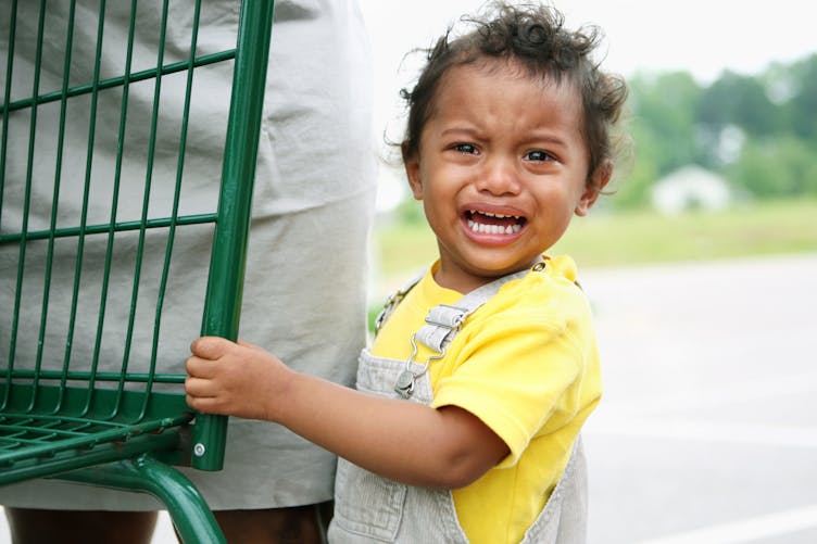 enfant qui pleure devant un supermarché