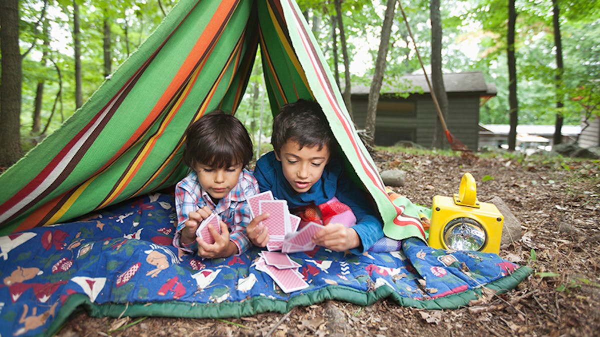 deux garçons jouent aux cartes sous une tente