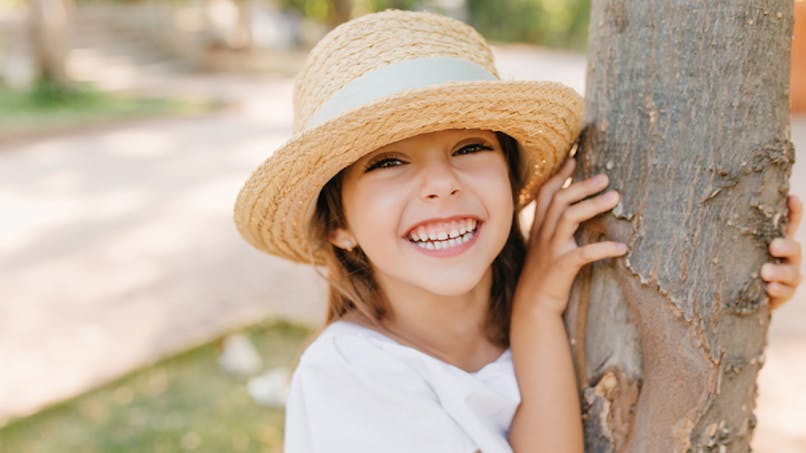 enfant souriante près d'un arbre