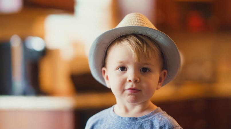 bébé en tee-shirt gris portant un chapeau