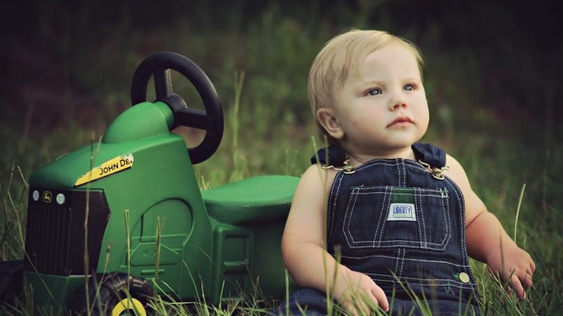 garçon à côté d'un mini tracteur pour enfants