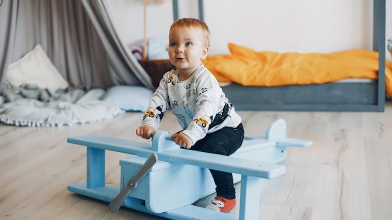 bébé joue avec un avion en bois