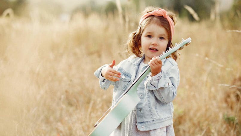 fille avec une guitare dans un champs