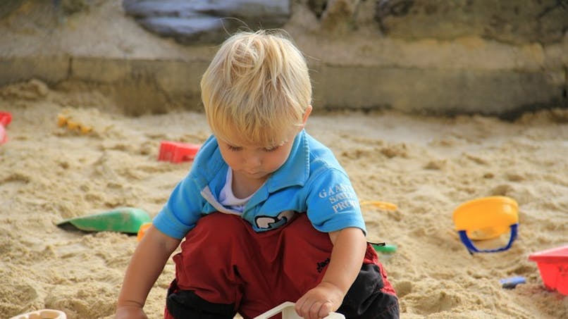 bébé joue sur la plage avec pelle et seau