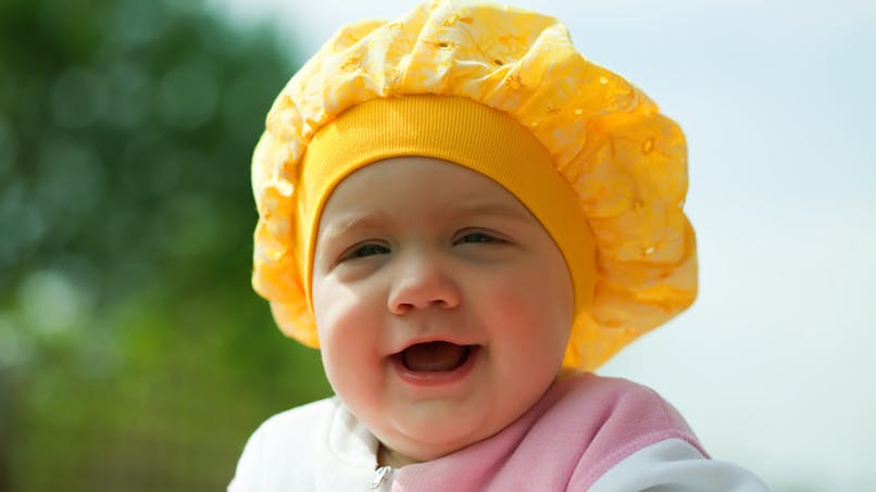 bébé avec une charlotte jaune sur la tete