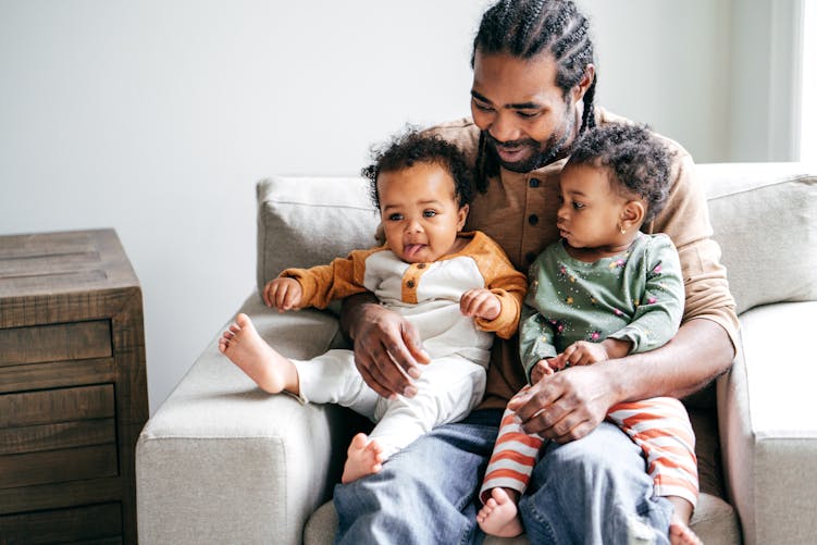 Nouveau congé paternité : un père tient deux bébés sur ses genoux
