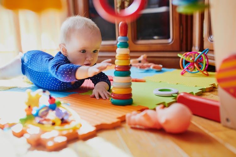 Un bébé curieux semble très attiré par ses jouets de construction