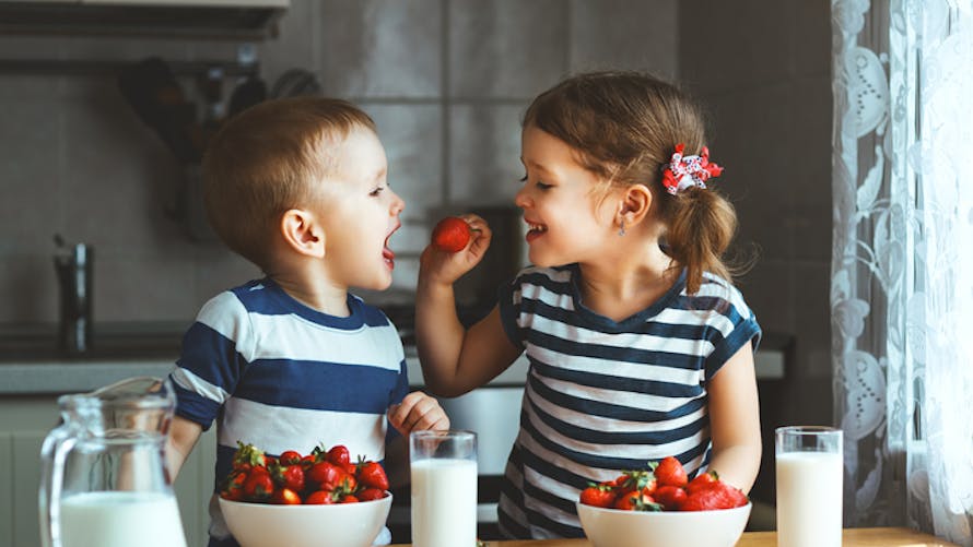 jumeaux fille et garçon goûtant des fraises
