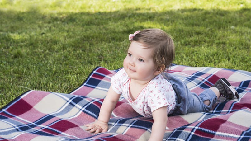 bébé est sur un plaid sur l'herbe