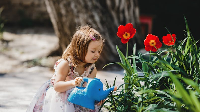 fille qui arrose des fleurs dans le jardin