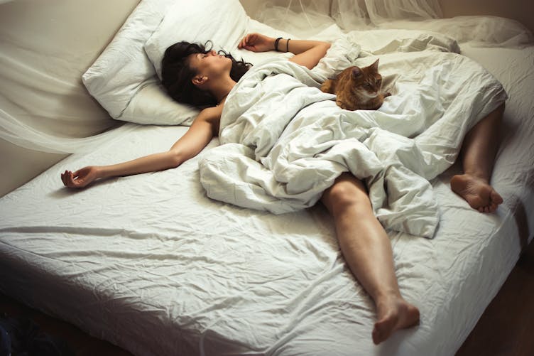 Une femme dort nue avec son chat