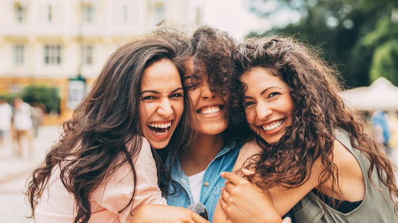 trois jeunes femmes riant et se tenant ensemble