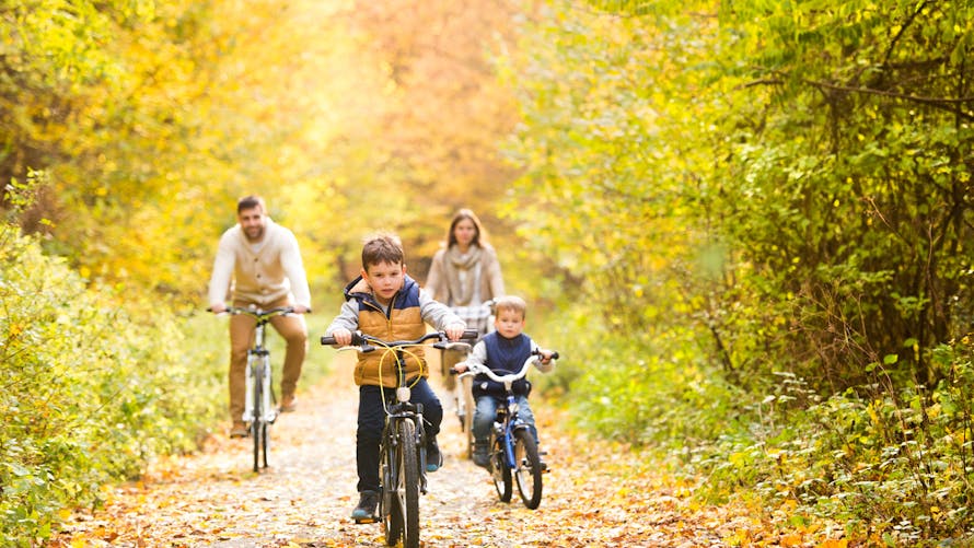 famille faisant du vélo en forêt à l'automne
