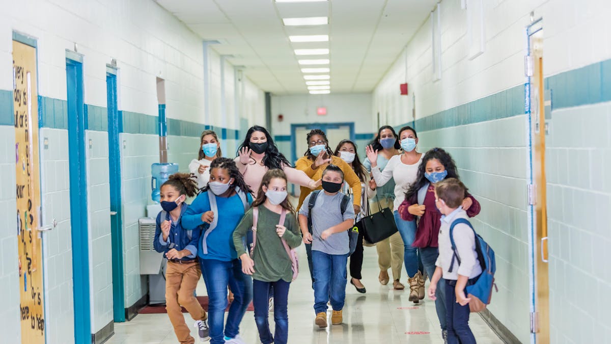 Des enfants courent dans un couloir d'école en portant des masques contre le Covid-19